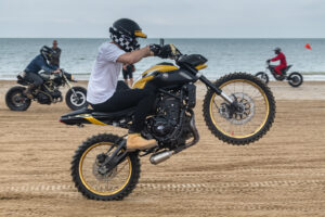 Rider wheelieing motorcycle along beach
