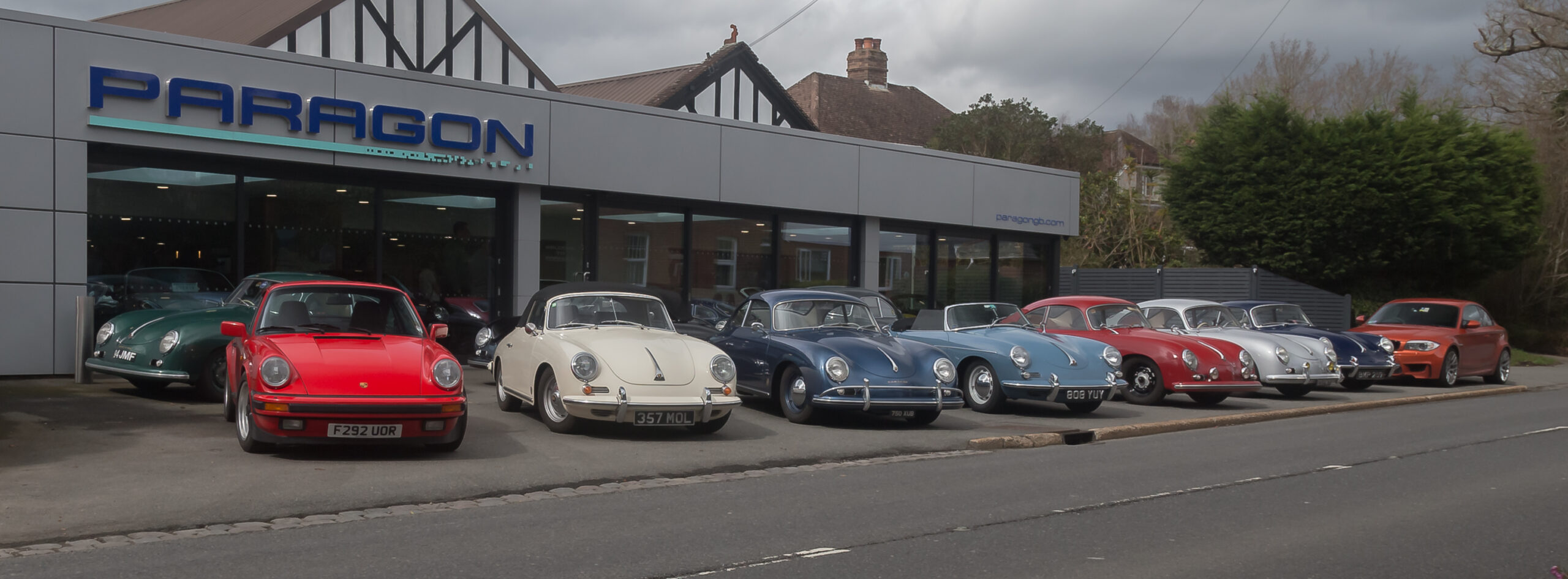 Classic Porsche sports cars lined up in front of Paragon Porsche dealership
